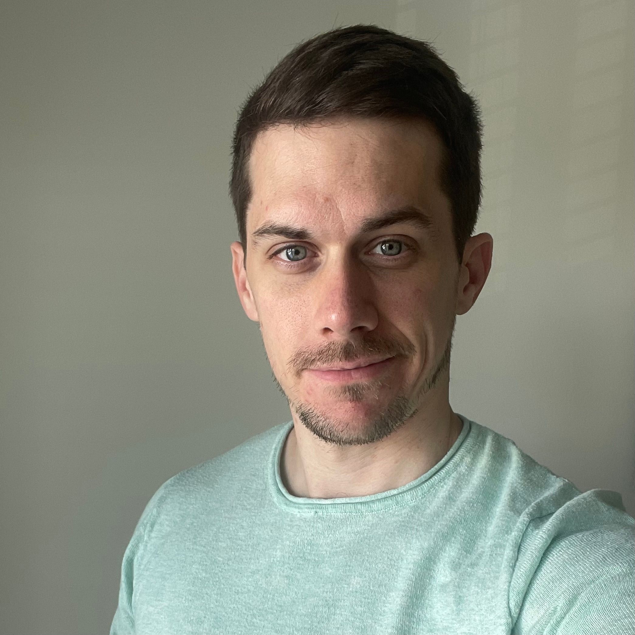 Bryan Cowan, smiling slightly, in a mint sweater against an olive-grey wall.